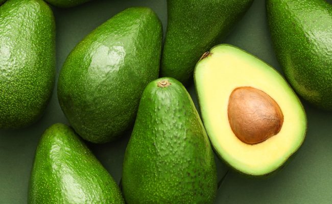 Fresh,Avocados,And,Palm,Leaves,On,Color,Background